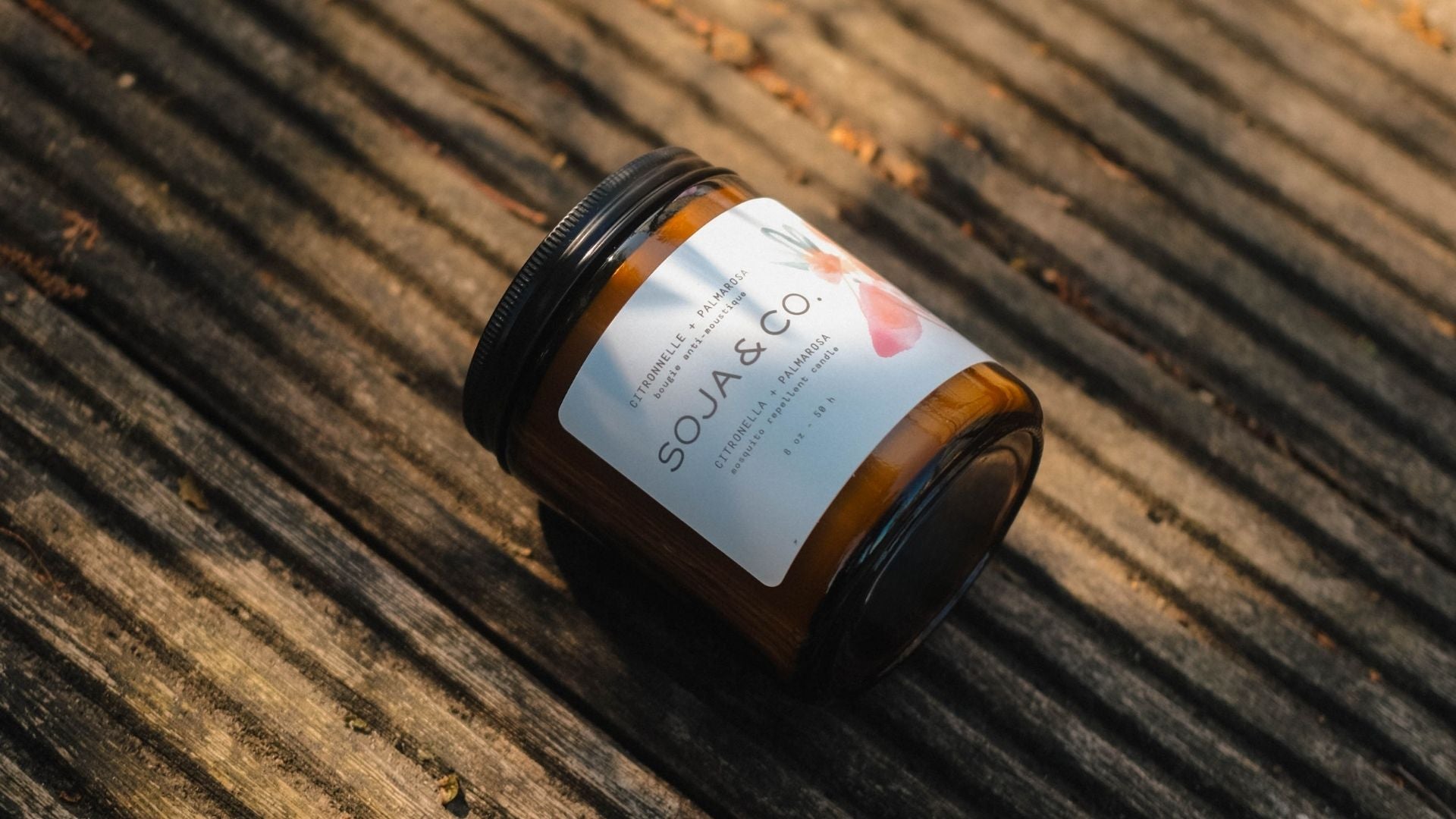 Bougie extérieure anti-moustique SOJA&CO. dans un pot en verre ambré, formulée à base d’huiles essentielles de citronnelle et de palmarosa