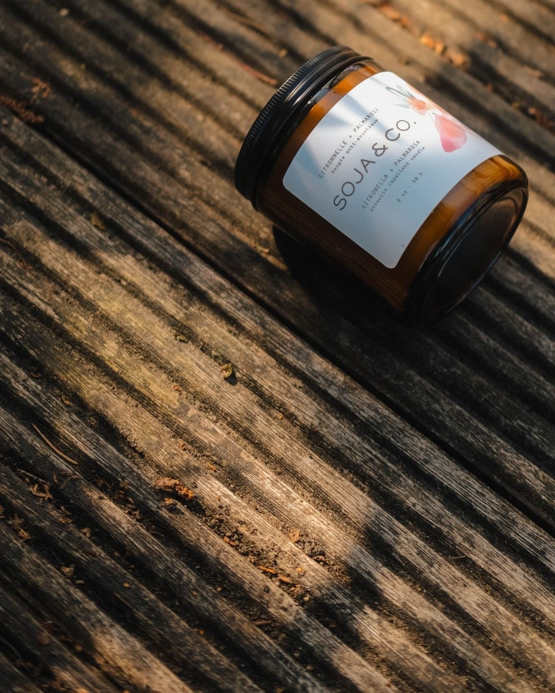 Bougie extérieure anti-moustique SOJA&CO. dans un pot en verre ambré, formulée à base d’huiles essentielles de citronnelle et de palmarosa